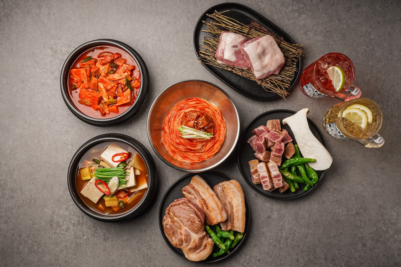 같은 상을 조금 더 넓게 찍은 사진. 찌개 두 가지와 생고기 접시, 반찬 종지 여러 개가 한 화면에 들어와 있다